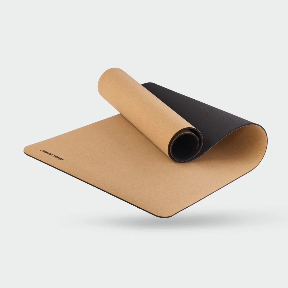 Two-tone cork and black yoga mat partially rolled, hovering above a light background