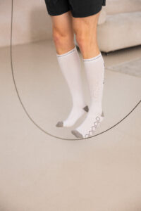 251122_DEUSER-20 - Deuser Sports | Solingen Person wearing white knee-high socks and black shorts, standing inside a circular or curved setting on a light floor.