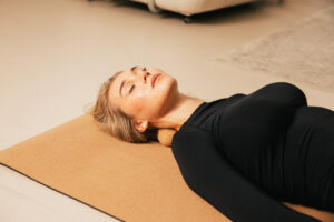 251122_DEUSER-60 - Deuser Sports | Solingen Woman lying on a cork yoga mat with eyes closed, resting in a relaxed position.